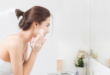 Kobieta w łazience przed lustrem myjąca twarz pianką do mycia twarzy