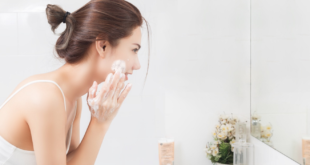 Kobieta w łazience przed lustrem myjąca twarz pianką do mycia twarzy