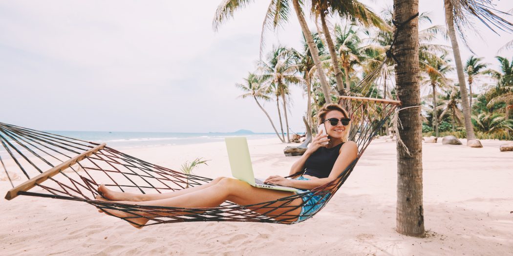 dziewczyna ze smartfonem i laptopem na egzotycznej plaży