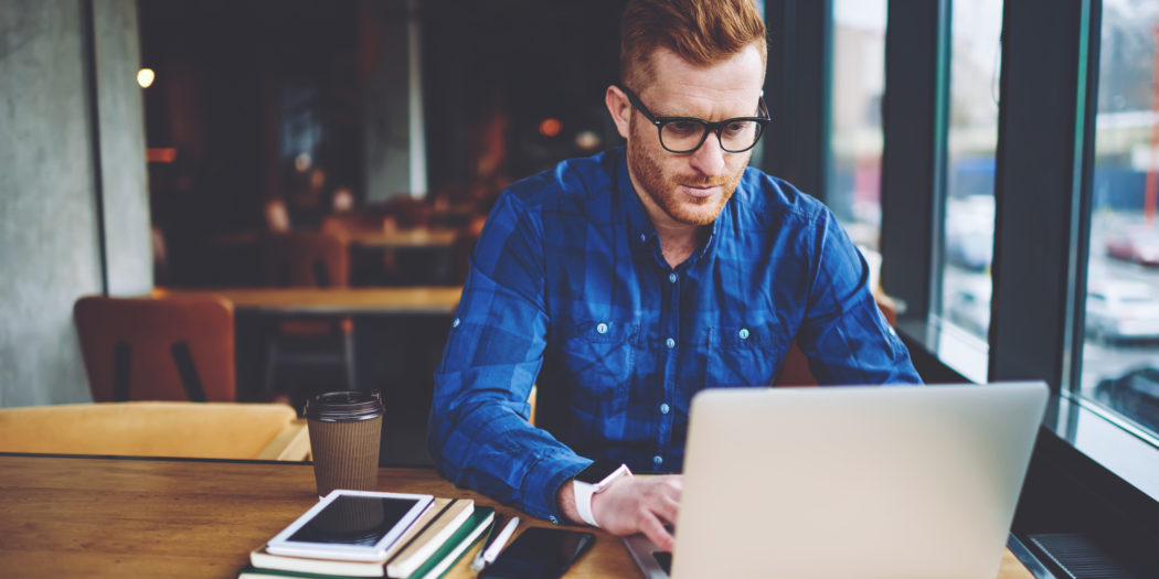 Mężczyzna wystawiający fakturę na laptopie w kawiarni