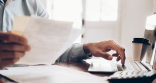 Mężczyzna wystawiający fakturę przed komputerem