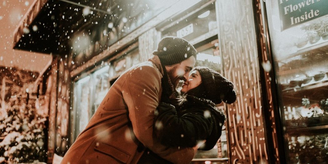 zakochana para obejmująca się zimą przed budynkiem