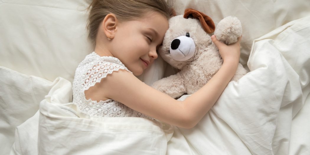 dziewczynka śpiąca z misiem na wygodnym materacu