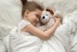 dziewczynka śpiąca z misiem na wygodnym materacu