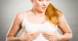 Kobieta z groźną miną trzyma się za piersi