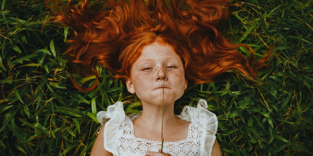 ruda dziewczynka leżąca na trawie
