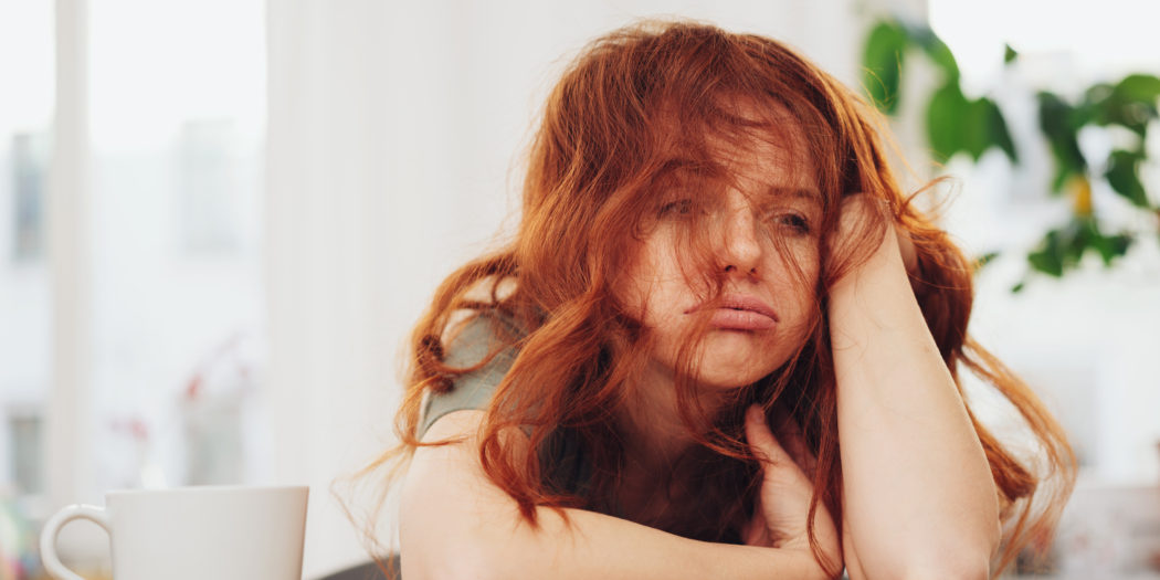 rudowłosa zmczna dziewczyna siedząca przy stole z kawą